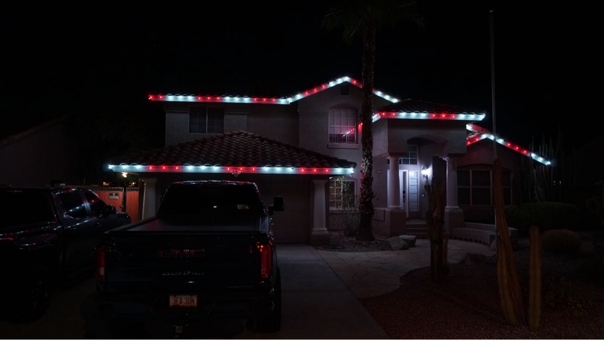 A two-story home with red and white roofline lights